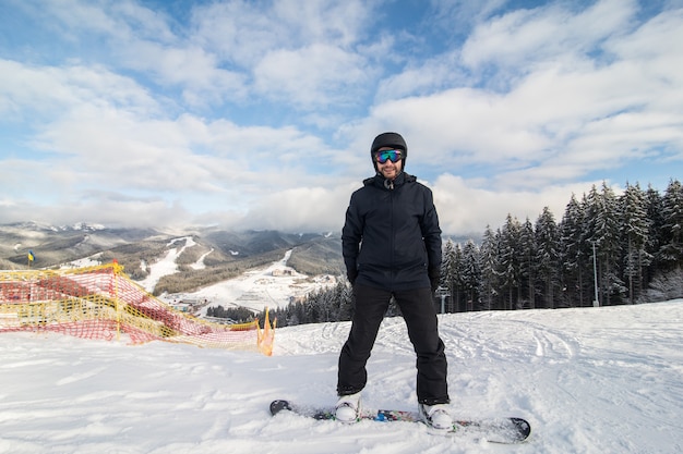Snowboarder deslizándose por la colina en la pista de paseo en la colina de las montañas