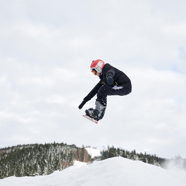 Snowboarder masculino haciendo trucos en el aire en la estación de esquí