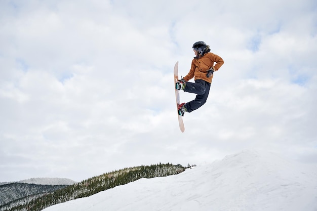 Snowboarder masculino haciendo trucos en el aire en la estación de esquí