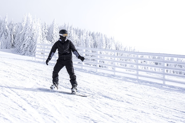 Snowboarder en movimiento bajando la colina en el resort de montaña