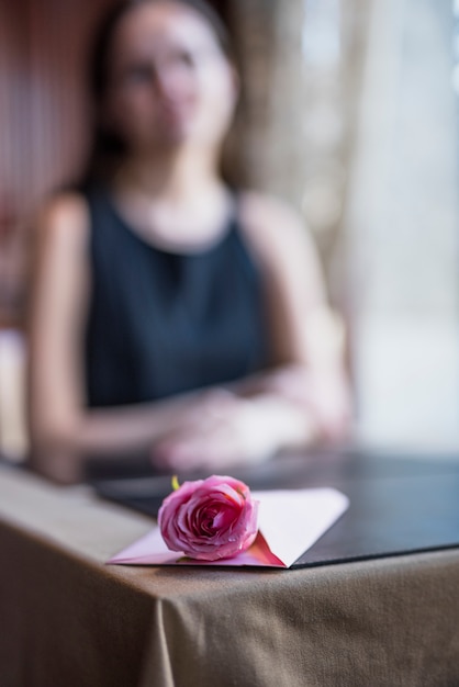 Sobre y flor en mesa cerca de mujer