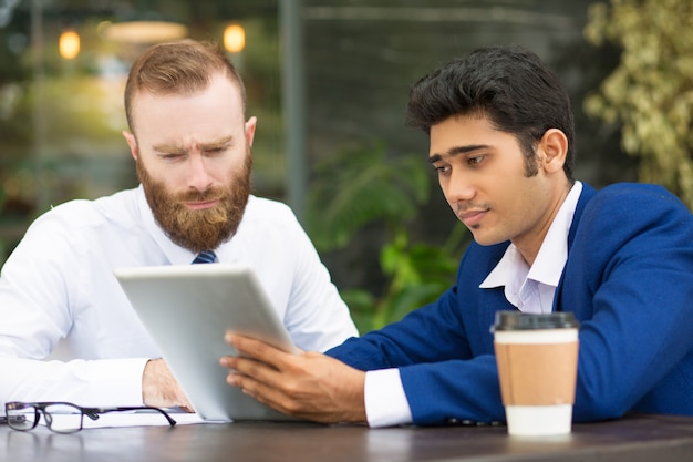 Socios comerciales multiétnicos concentrados usando tableta