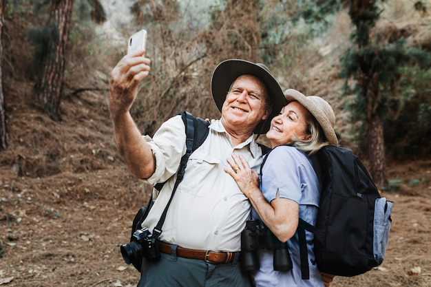 Socios senior tomando selfie en el bosque