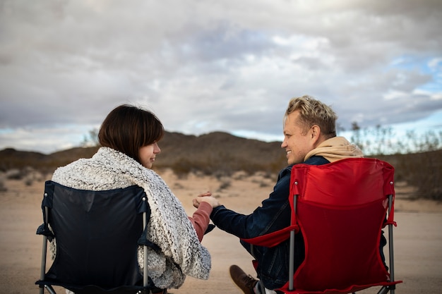 Foto gratuita socios de tiro medio sentados en sillas en el desierto