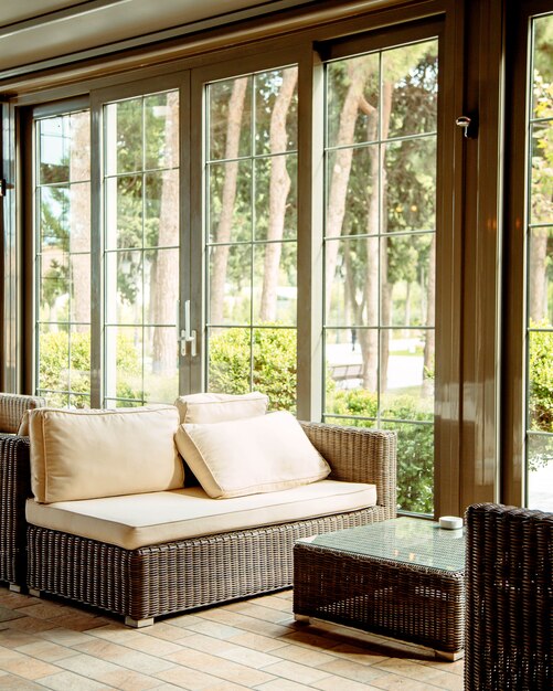Sofá al aire libre con cojines de color beige y mesa de café frente a la ventana del restaurante.