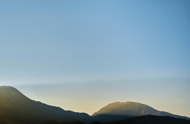 El sol al amanecer ilumina las montañas temprano en la mañana en las montañas de la costa mediterránea fondo de idea de publicidad de vacaciones para una pantalla de presentación con espacio libre