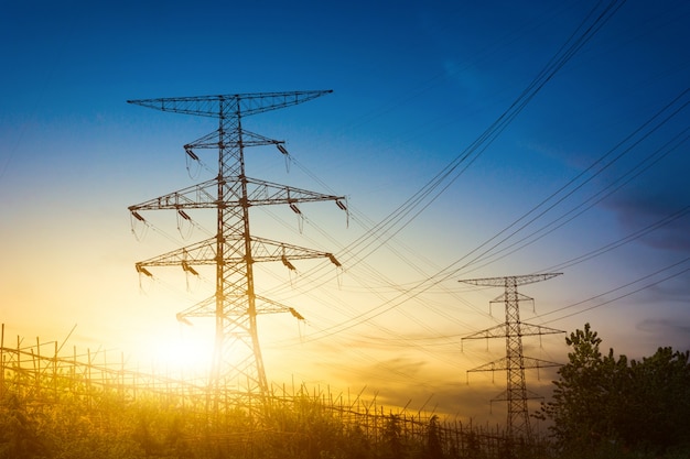 Sol detrás de la silueta de las torres de electricidad