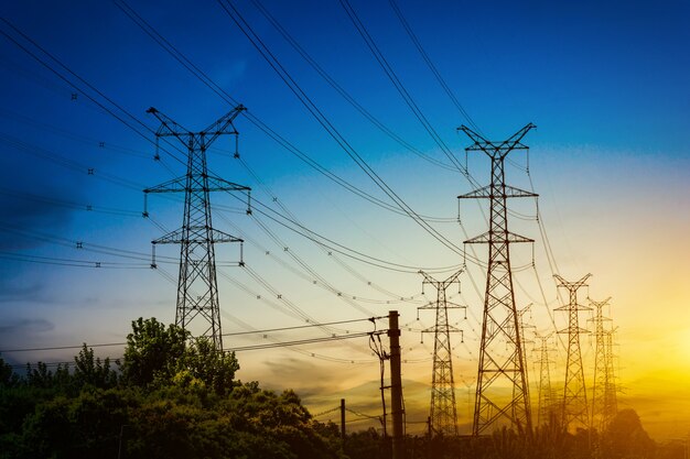 Sol detrás de la silueta de las torres de electricidad