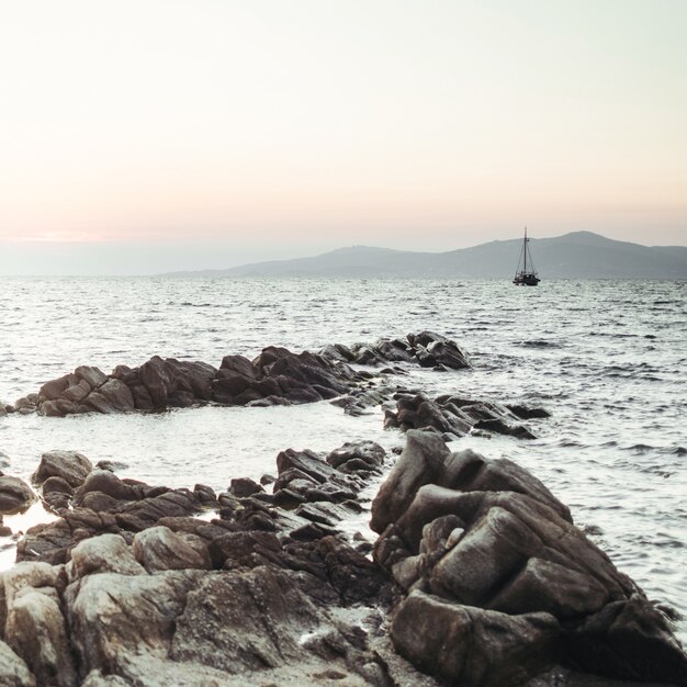 El sol se pone sobre el mar y las rocas negras ante él.