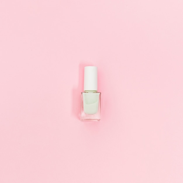 Sola botella de esmalte de uñas blanco sobre fondo rosa