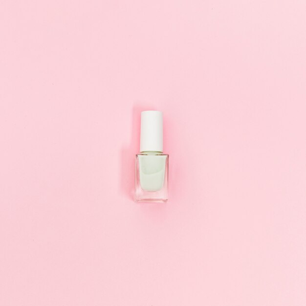 Sola botella de esmalte de uñas blanco sobre fondo rosa