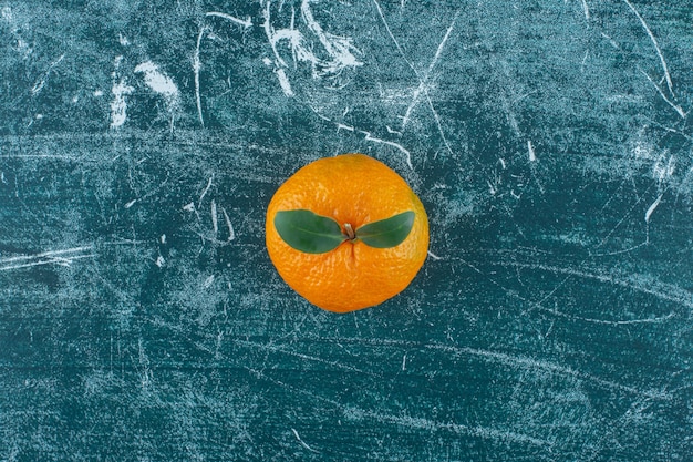 Una sola mandarina jugosa, sobre la mesa de mármol.