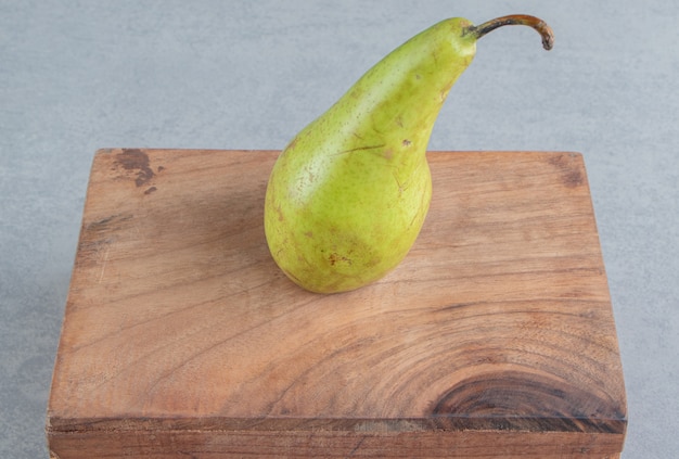 Una sola pera sobre una tabla de madera sobre mármol