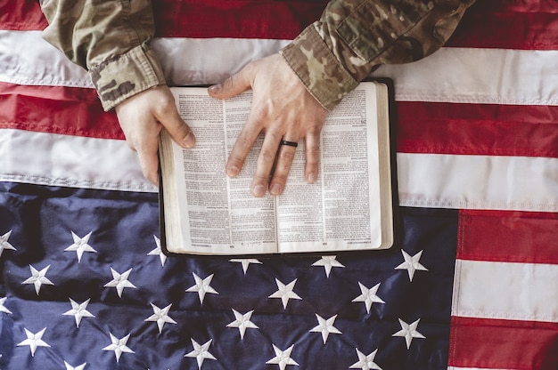 Foto gratuita soldado americano llorando y rezando con la biblia en sus manos y la bandera americana