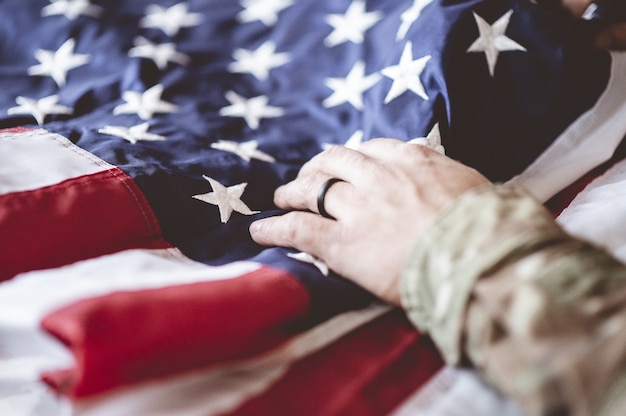 Foto gratuita soldado estadounidense llorando y rezando con la bandera estadounidense frente a él