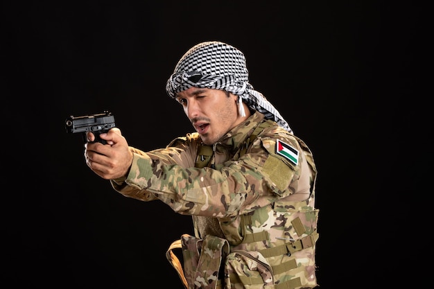Soldado palestino apuntando con pistola a la pared negra