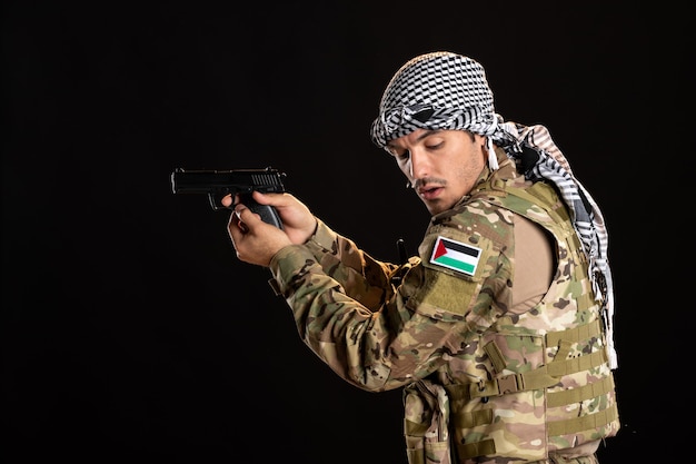 Soldado palestino apuntando con pistola a la pared negra