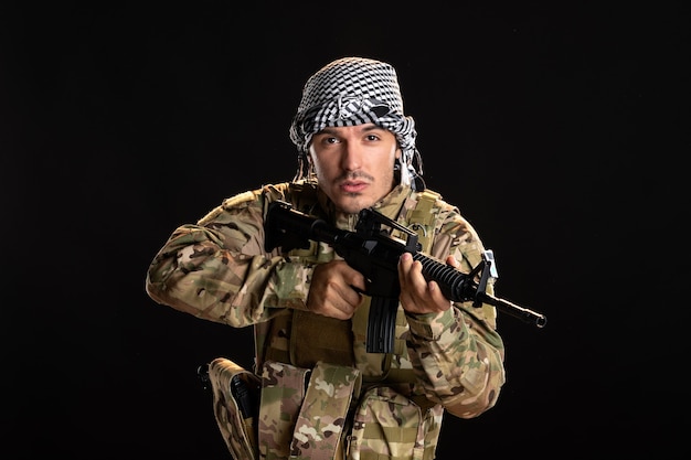 Soldado palestino en camuflaje luchando con ametralladora en pared negra