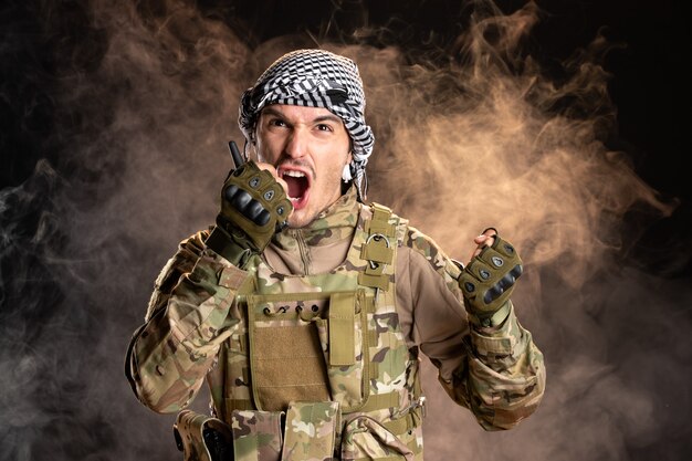 Soldado palestino gritando a través de radioset en pared oscura