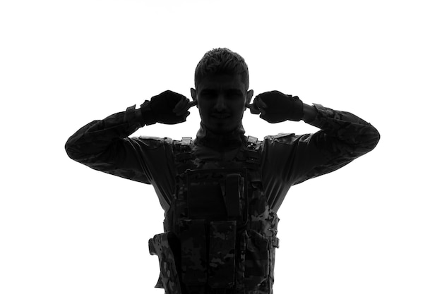 Soldado silueta serio guapo fuerte duro ejército soldado en uniforme cubriendo las orejas