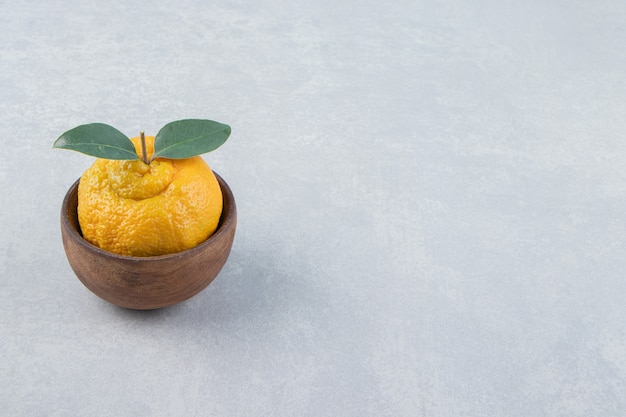 Solo mandarina fresca con hojas en tazón de madera