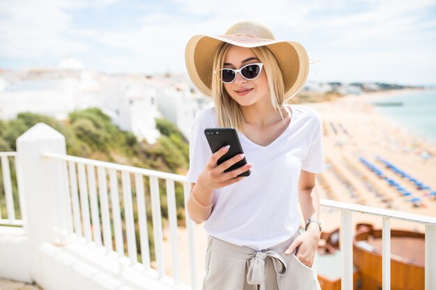 Solo niña feliz comprobando un teléfono inteligente sentado en un bar en la terraza