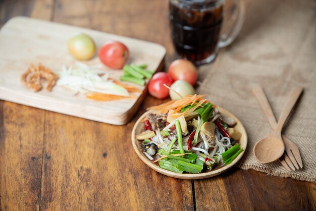 Som Tam Thai, ensalada de papaya tailandesa sobre fondo de madera