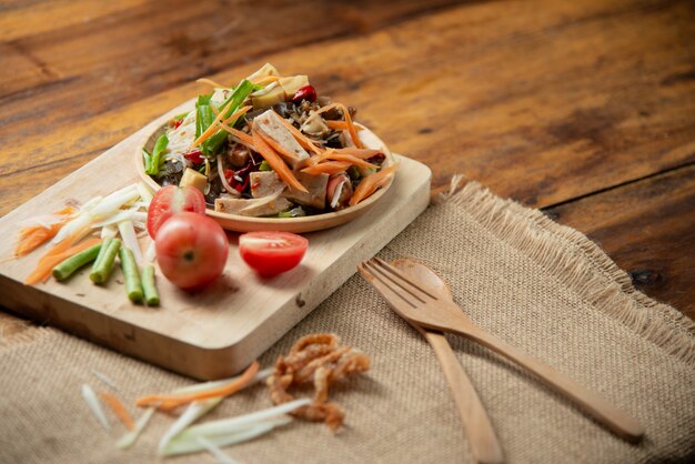 Som Tam Thai, ensalada de papaya tailandesa sobre fondo de madera