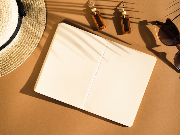 Sombra de hoja de palma con gafas de sol negras y cuaderno blanco