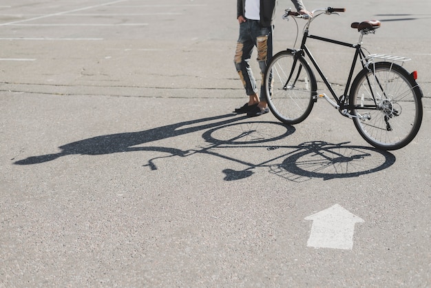 Sombra del hombre de pie con bicicleta en la carretera