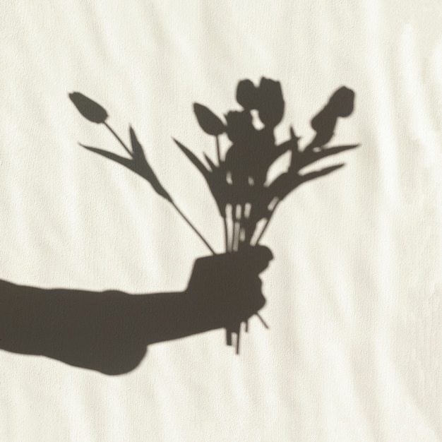 Sombra de mano sosteniendo tulipanes