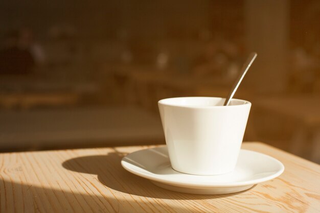 Sombra de la taza de café y platillo en el escritorio de madera