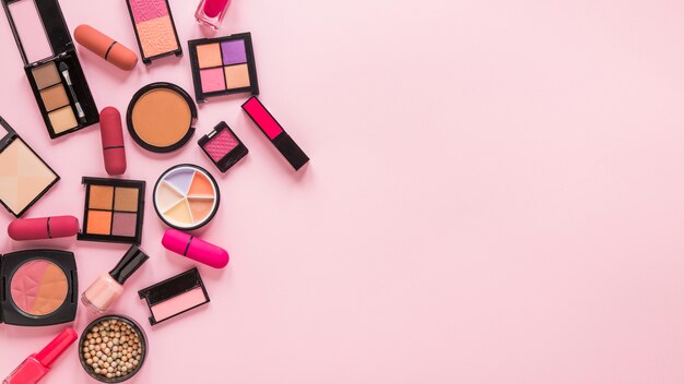 Sombras de ojos con lápices labiales en mesa rosa.