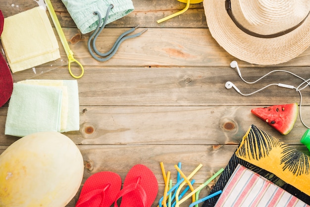 Sombrero cerca de auriculares y chanclas con frutas y bolsa de vacío.