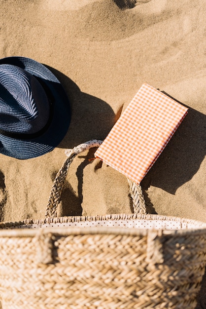 Sombrero, cesta y diario en la playa