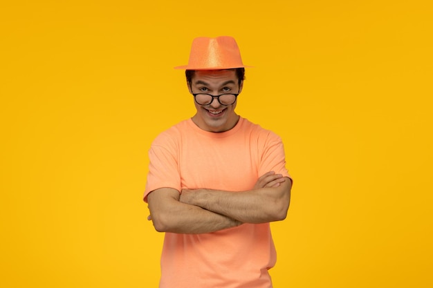 Sombrero naranja guapo chico guapo en camiseta naranja con el sombrero mirando por encima de las gafas