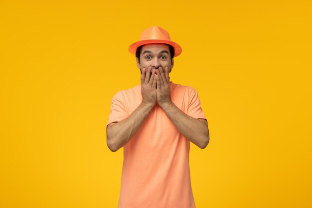 Sombrero naranja lindo chico joven con camisa naranja con el sombrero súper emocionado y cubriendo la boca