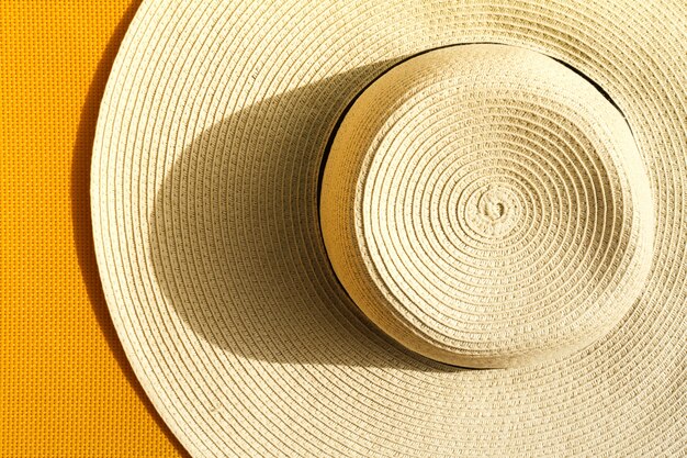 Sombrero de paja hermoso con en fondo vivo vibrante amarillo. Vista superior. Concepto De Las Vacaciones De Viaje De Verano.