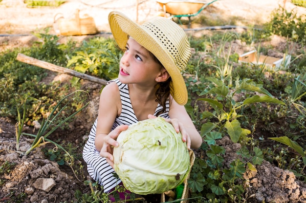 Sombrero que lleva de la mujer que sostiene la col en el campo