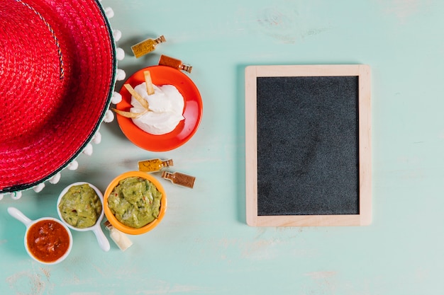 Sombrero rojo y salsas cerca de la pizarra