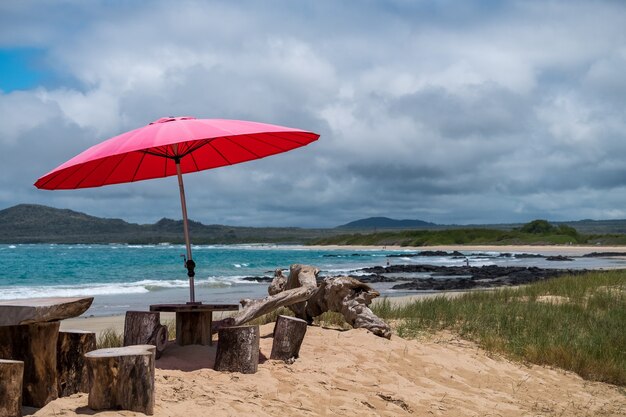 Sombrilla roja que proporciona sombra para la gente en la playa en las Islas Galápagos, Ecuador