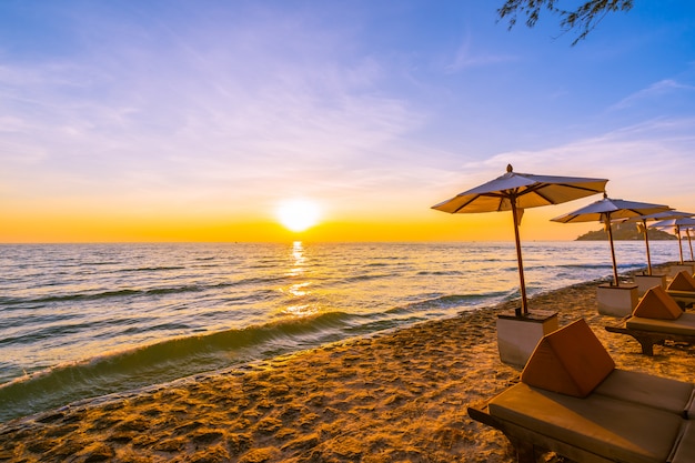 Sombrilla y silla con almohada alrededor del hermoso paisaje de playa y mar.