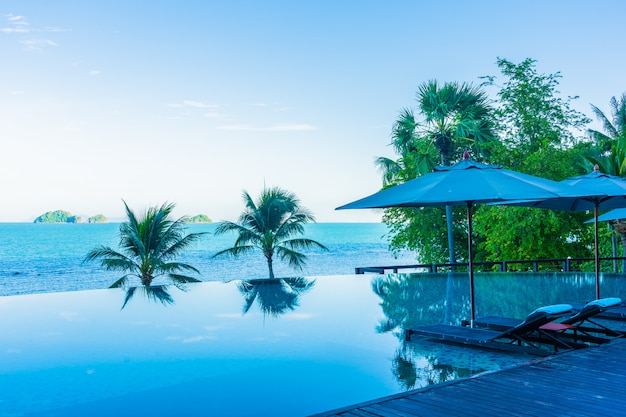 Sombrilla y silla alrededor de la hermosa piscina de lujo al aire libre con vista al mar en el resort del hotel para viajes de vacaciones