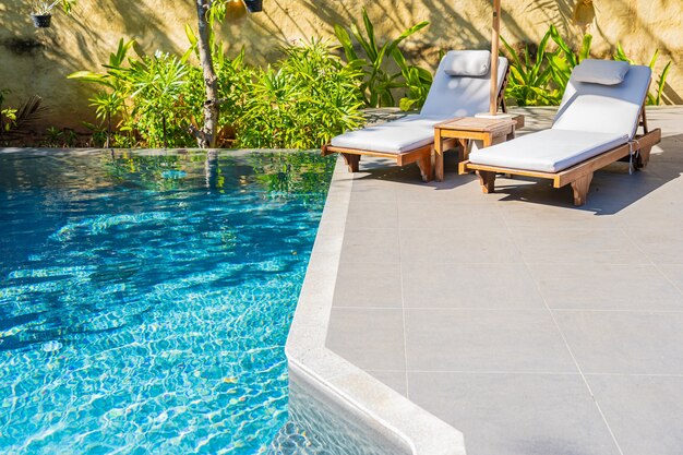 Sombrilla y silla alrededor de la piscina al aire libre en el hotel resort para el ocio vacacional