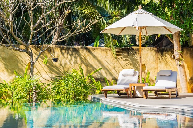 Sombrilla y silla alrededor de la piscina al aire libre en el hotel resort para el ocio vacacional