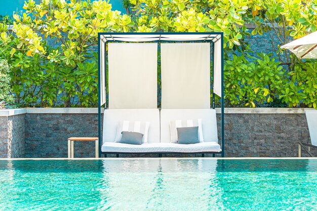 Sombrilla y silla alrededor de la piscina al aire libre en el hotel resort para viajes de placer concepto de vacaciones