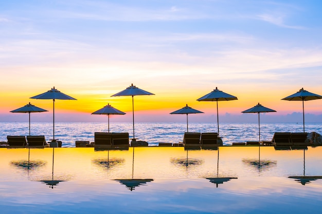 Foto gratuita sombrilla y silla alrededor de la piscina en el hotel resort para viajes de placer y vacaciones