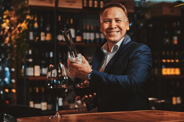 El sommelier de vinos feliz y sonriente está listo para probar un nuevo vino tinto en la boutique de vinos artesanales.