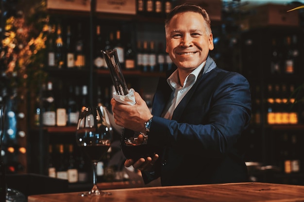 Foto gratuita el sommelier de vinos feliz y sonriente está listo para probar un nuevo vino tinto en la boutique de vinos artesanales.