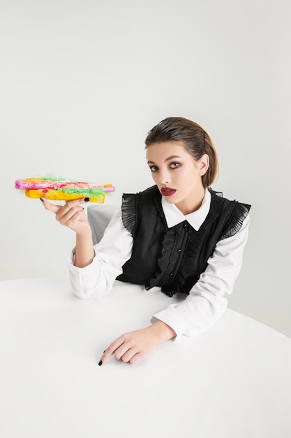 Somos lo que comemos. Mujer comiendo hot-dog de plástico, concepto ecológico